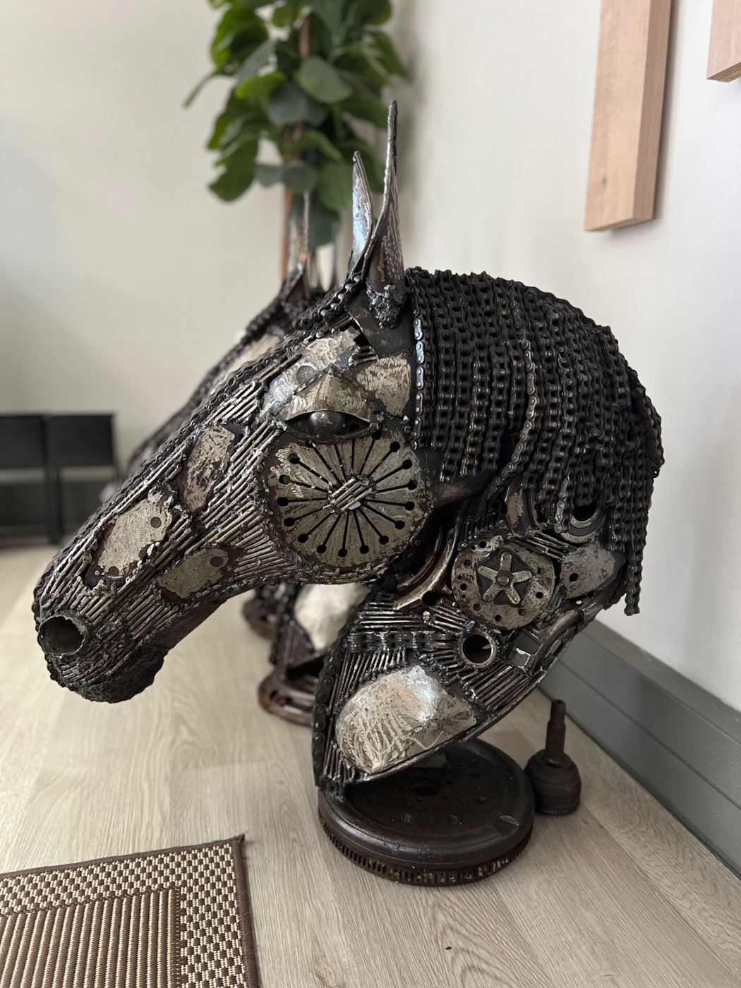 Steel horse head sculpture with a chain mane on a flywheel base